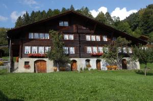 ein großes Holzhaus auf einem grünen Feld in der Unterkunft Haus Gerbi in Hasliberg