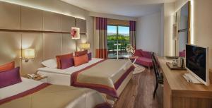 um quarto de hotel com duas camas e uma secretária em Botanik Hotel em Okurcalar
