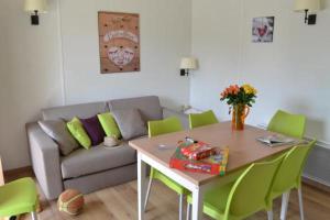 a living room with a couch and a table with green chairs at VVF Les Ecrins Champsaur in Saint-Bonnet-en-Champsaur
