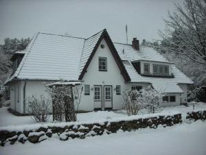 una casa blanca con nieve en el techo en Ferienwohnungen Outzen, en Nebel