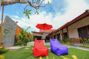 twee kleurrijke stoelen op het gras met een paraplu bij Rahma Guesthouse in Canggu