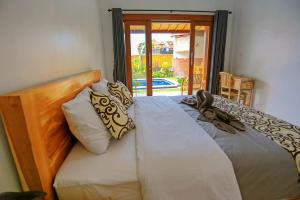 een slaapkamer met een bed en een glazen schuifdeur bij Rahma Guesthouse in Canggu