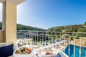 a balcony with a table and chairs and a pool at Viewpoint Boutique Living in Xlendi