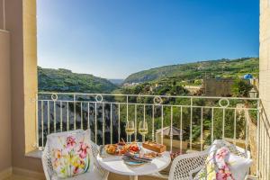 a balcony with a table with food and wine glasses at Viewpoint Boutique Living in Xlendi