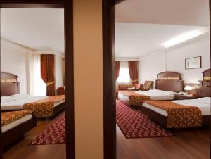 Habitación de hotel con 3 camas y sala de estar. en Botanik Hotel, en Okurcalar