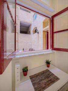 Habitación con ventana y 2 macetas. en Valletta Main Street Apartment en La Valeta