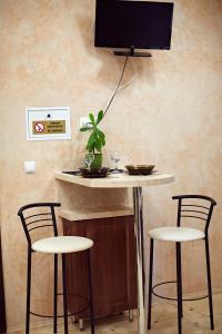 a table with three chairs and a tv on a wall at Babylon Apartments On Dubenska Street in Rivne