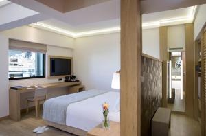 una camera d'albergo con letto, scrivania e TV di Golden Age Athens Hotel ad Atene