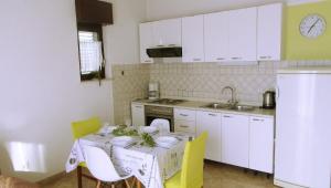a kitchen with a table with yellow chairs and white cabinets at Apartments Maletić in Kaštela