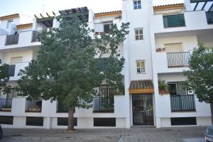apartamentowiec z drzewem przed nim w obiekcie Apartamento en zona Atalaya con garaje y WIFI w mieście Conil de la Frontera