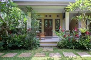 a front porch of a house with a chair and flowers at Telaga Homestay Ubud in Ubud