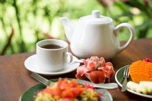 uma mesa com uma chávena de café e um prato de fruta em Telaga Homestay Ubud em Ubud