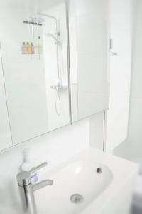 a white bathroom sink with a shower and a mirror at Nieuwpoortnachten res. Westdiep Dominique in Nieuwpoort +29 photos