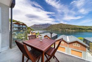a wooden table on a balcony with a view of the water at Alpine Village - 2 Bedroom Executive Apartment in Queenstown
