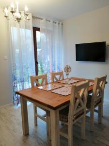 a dining room table with chairs and a television at Apartamenty Homole C2 Szczawnica in Szczawnica