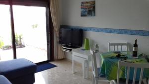 ein kleines Wohnzimmer mit einem Tisch und einem TV in der Unterkunft AMAZING SEASIDE DUPLEX IN THE GREEN SOUTH TENERIFE in San Miguel de Abona