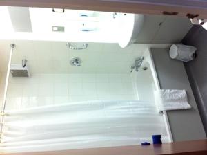 a bathroom with a shower with a white tiled wall at Days Inn Hotel Bradford - Leeds in Brighouse