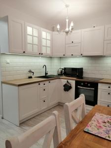 a kitchen with white cabinets and a wooden table at Apartamenty Homole C2 Szczawnica in Szczawnica