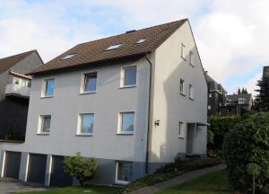ein weißes Haus mit braunem Dach in der Unterkunft Gästehaus Schönenberg in Wuppertal