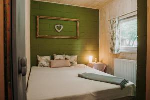 a bedroom with a bed with a green wall at Vackorkert in Sirok