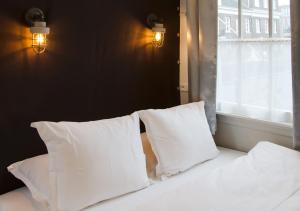 uma cama com almofadas brancas ao lado de uma janela em SWEETS - Scharrebiersluis em Amsterdã