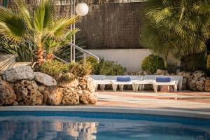 a swimming pool with lounge chairs and palm trees at htop Olympic - Fun in Calella +29 photos
