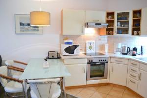 eine Küche mit weißen Schränken und einem Tisch mit Stühlen in der Unterkunft Haus Sonnenhof Bansin in Bansin + 4 Fotos