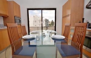 une salle à manger avec une table et des chaises en verre dans l'établissement City Living Suite Tk 3 Rm 3, à San Ġiljan