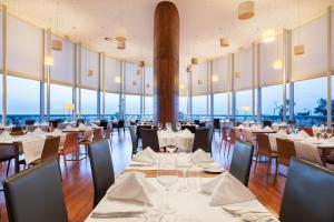 ein Restaurant mit weißen Tischen und Stühlen und großen Fenstern in der Unterkunft Eurostars Oasis Plaza in Figueira da Foz + 71 Fotos