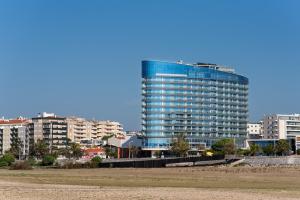 um edifício azul alto em frente a alguns edifícios em Eurostars Oasis Plaza na Figueira da Foz