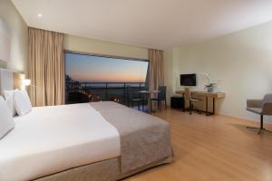 ein Hotelzimmer mit einem Bett und einem großen Fenster in der Unterkunft Eurostars Oasis Plaza in Figueira da Foz