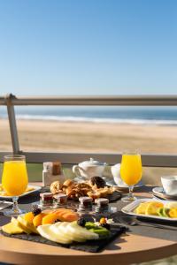 ein Tisch mit Tellern mit Essen und zwei Gläsern Orangensaft in der Unterkunft Eurostars Oasis Plaza in Figueira da Foz