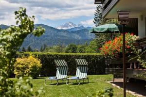 twee stoelen en een paraplu in een tuin met een berg bij Lake Bled Apartment Marjetka in Bled