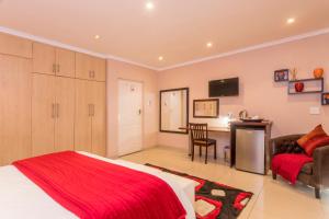 a bedroom with a bed and a desk with a chair at Ezulwini Guest House in Ballito