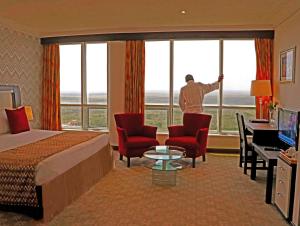 um quarto de hotel com um homem a olhar pela janela em The Panari Hotel - Near Jomo Kenyatta International Airport em Nairobi