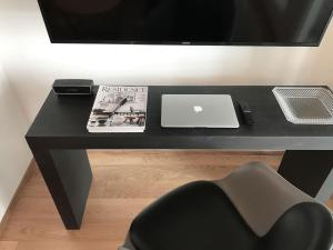 a black desk with a laptop and a magazine at Helsinki 00100 Vuorikatu 40,5 m2 in Helsinki