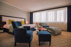 a hotel room with a bed and chairs and a table at The Panari Hotel Nairobi in Nairobi