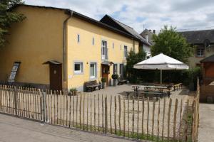 a yellow house with a fence and an umbrella and picnic tables at Nengshof Ferienhäuser Sonnenblume und Heublume in Wißmannsdorf