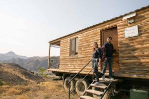 two people standing on the stairs of a log cabin at Arpa Valley Cabin in Yeghegnadzor