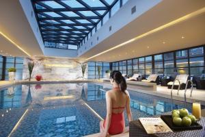 una donna seduta davanti a una piscina di Ascott Huai Hai Road Shanghai, Xintiandi a Shanghai