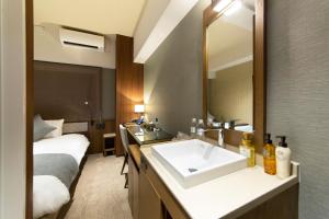 baño con lavabo, cama y espejo en HOTEL HILLARYS Shinsaibashi en Osaka