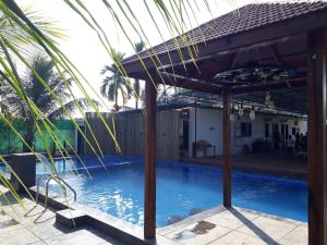a pool with a pergola next to a house at Sea Land Kihim in Alibaug