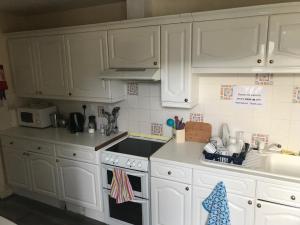 a kitchen with white cabinets and a stove top oven at The Mission Bunkhouse in Mallaig