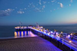 a pier with lights on the water at night at Delphin Imperial Lara in Lara