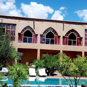 a building with two chairs in front of a pool at Bassatine Skoura in Skoura