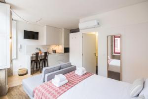 a bedroom with a large white bed and a kitchen at Oporto Sweet Home III in Porto