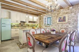 cocina con mesa, sillas y pared de piedra en Villa Princess Captislava, en Cavtat