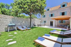 een achtertuin met een stenen muur en stoelen en een grill bij Villa Princess Captislava in Cavtat