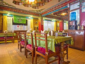 comedor con mesa verde y sillas en hotel Seven Seventeen, en Darjeeling