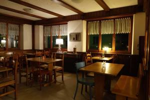 een restaurant met houten tafels, stoelen en ramen bij Pension Bellevue Gondo in Ruden